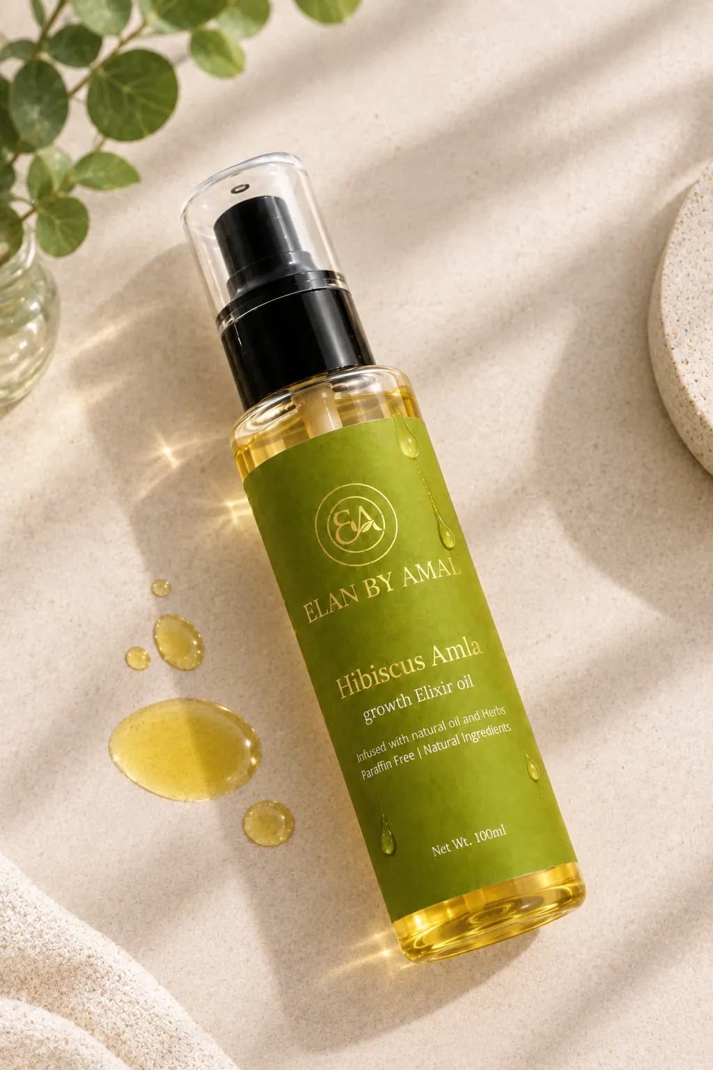 Hibiscus Amla Growth Elixir Oil lying on sand-coloured stone with golden oil droplets
